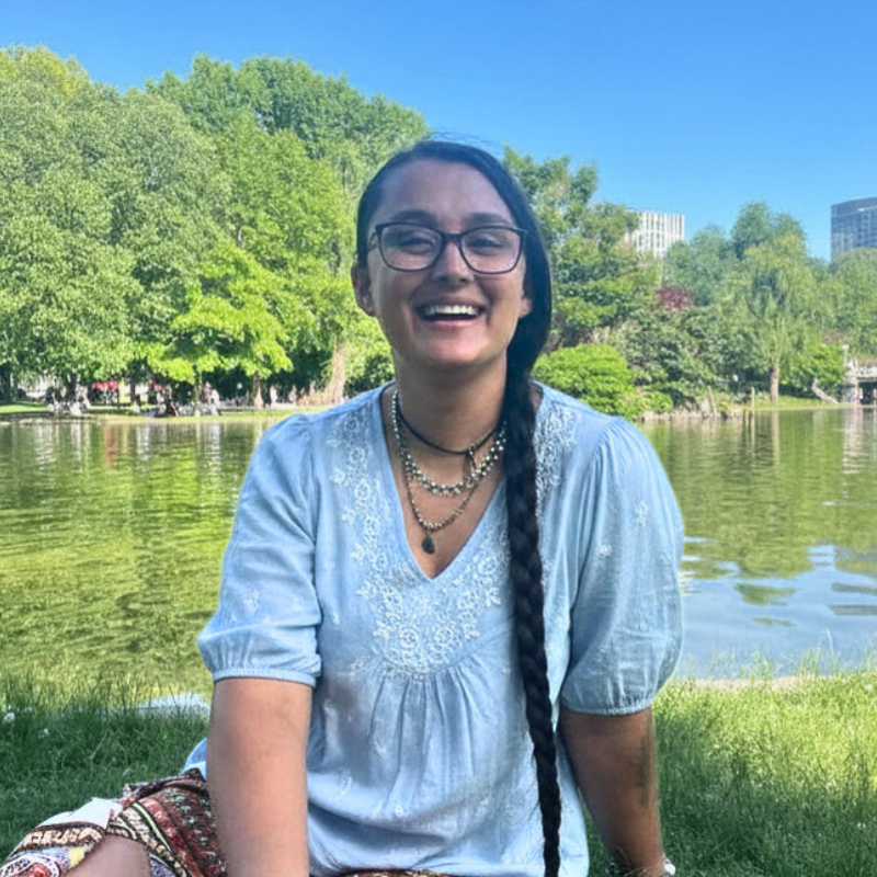 Maya sits in front of a lake